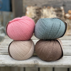 Four balls of yarn. Colours are beige, pink, teal and brown