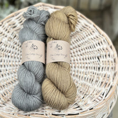 Two skeins of yarn - one grey skein and one brown skein