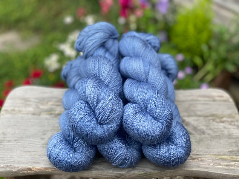 Five skeins of fine blue yarn resting on a wooden stool