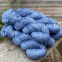 Five skeins of fine blue yarn resting on a wooden stool