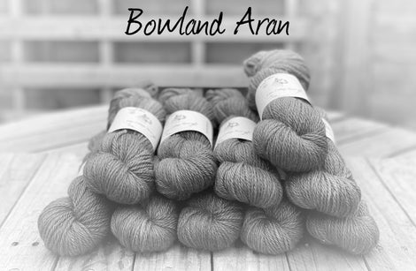 Black and white image of skeins of yarn with "Bowland Aran" overlaid in black text