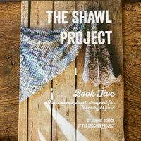 Shawl Project Book Five resting on a wooden bench 