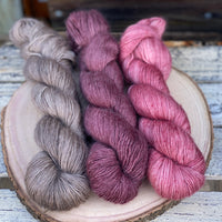Three skeins of yarn used to make the Swainby Cowl. Yarns are in shades of red and brown