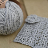 Pale blue yarn alongside a knitted square