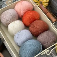 Eight balls of Milburn 4ply in shades of orange, brown and blue