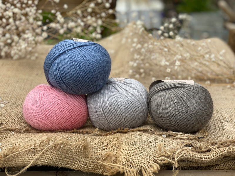 Four balls of yarn. Colours are pink, blue, light blue and grey