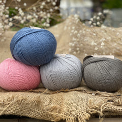 Four balls of yarn. Colours are pink, blue, light blue and grey