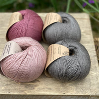 Four balls of yarn in grey and pinks