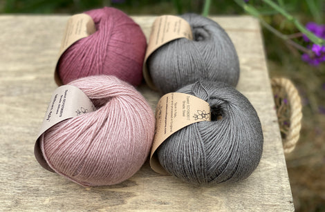 Four balls of yarn in grey and pinks