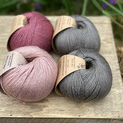 Four balls of yarn in grey and pinks