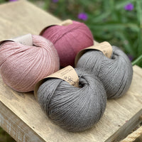 Four balls of yarn in grey and pinks