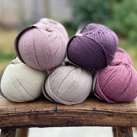 10 balls of yarn in five colours, a fade of pink/purple