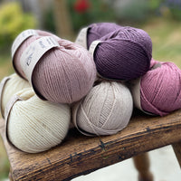 10 balls of yarn in five colours, a fade of pink/purple