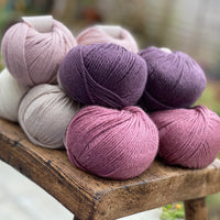 10 balls of yarn in five colours, a fade of pink/purple