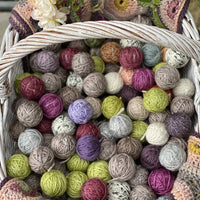 A basket of small balls of yarn in various colours