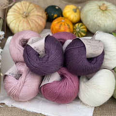 Eight balls of yarn in four colours, two each of natural cream, pale pink, dark pink and dark purple