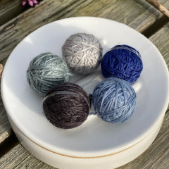 Five small balls of yarn in blues and greys