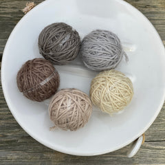 Five small balls of yarn in neutral shades