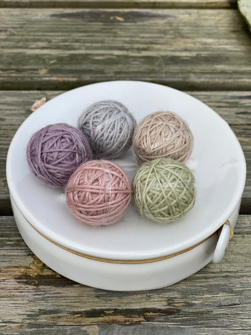 Five small balls of yarn in pastel shades