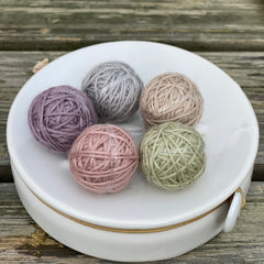 Five small balls of yarn in pastel shades