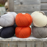 Ten balls of Milburn in shades of grey with a pop of orange