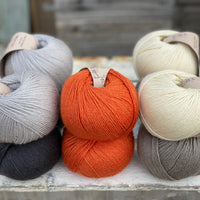 Ten balls of Milburn in shades of grey with a pop of orange
