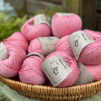 A basket filled with balls of pink yarn