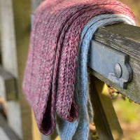 Two Swainby Cowls draped over a wooden gate. One is red and one is blue