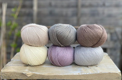 Six balls of yarn in soft neutrals including pale purple