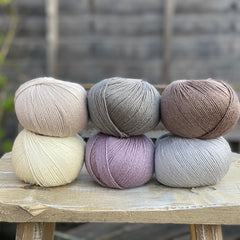 Six balls of yarn in soft neutrals including pale purple