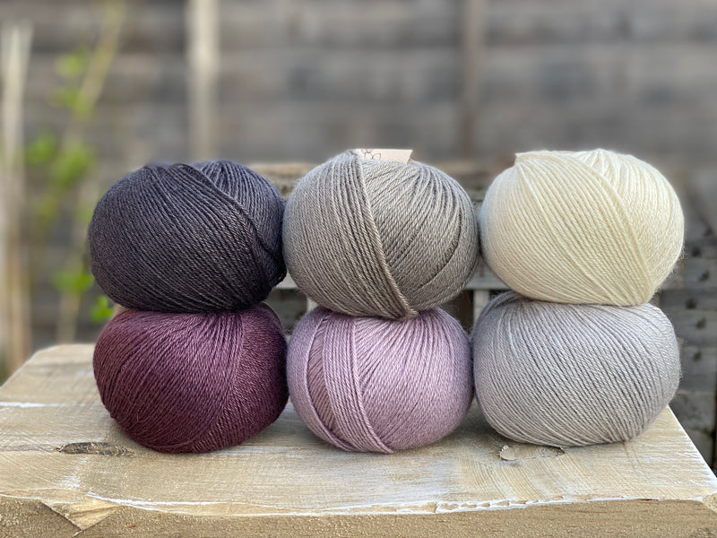 Six balls of Milburn 4ply in shades of grey, cream and purple