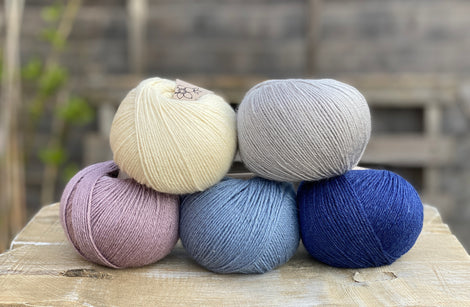 Five balls of yarn in shades of blue and purple