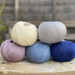 Five balls of yarn in shades of blue and purple