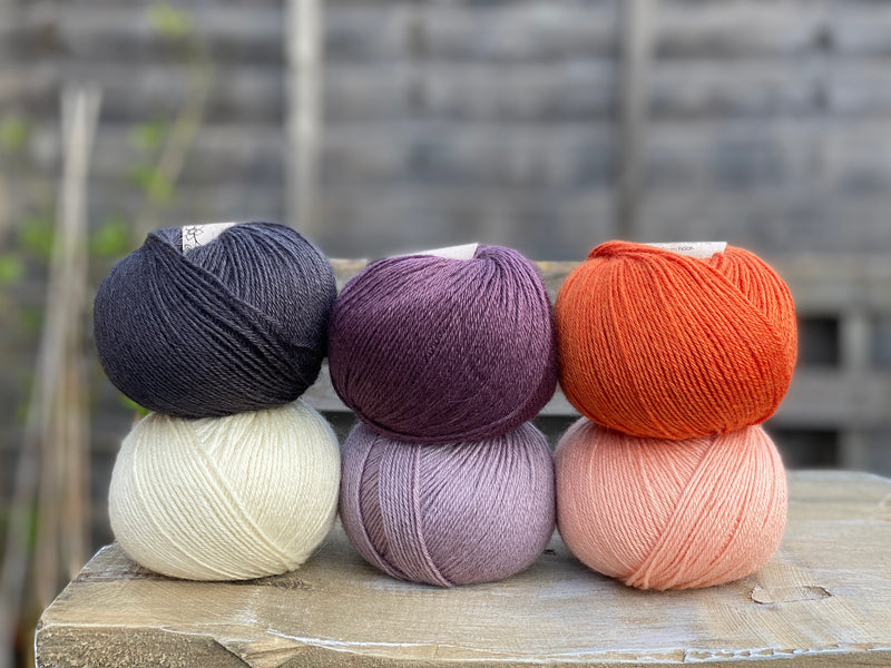 Six balls of yarn in purple, orange, black and white