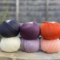 Six balls of yarn in purple, orange, black and white