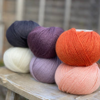 Six balls of yarn in purple, orange, black and white