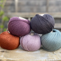 Five balls of Milburn 4ply in purple, grey, green and rust.