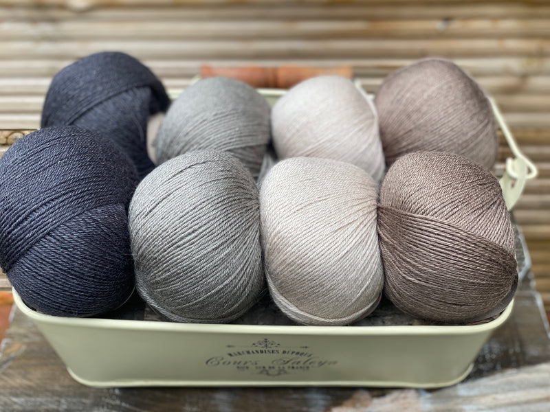 Eight balls of yarn in four pairs. From left to right the colourways are black, grey, beige and brown